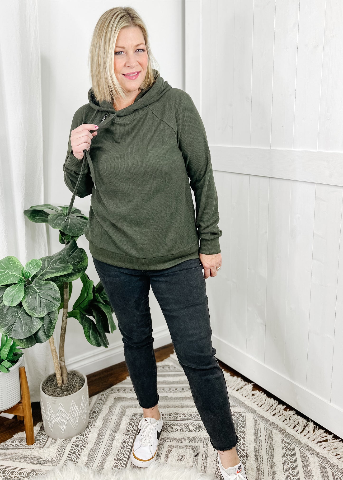 Olive hoodie in a heavy thermal. Top features a side hoodie (opening on the right between center and shoulder) with functional drawstrings and zipper detail also on the side below hoodie opening. Top is long sleeved.