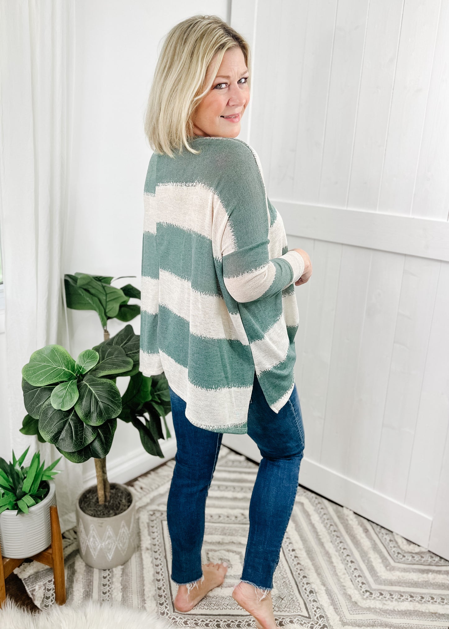 Sage green striped top with contrasting cream stripes, stripes are wide and fade into each other. V-neckline, drop shoulder and relaxed fit.