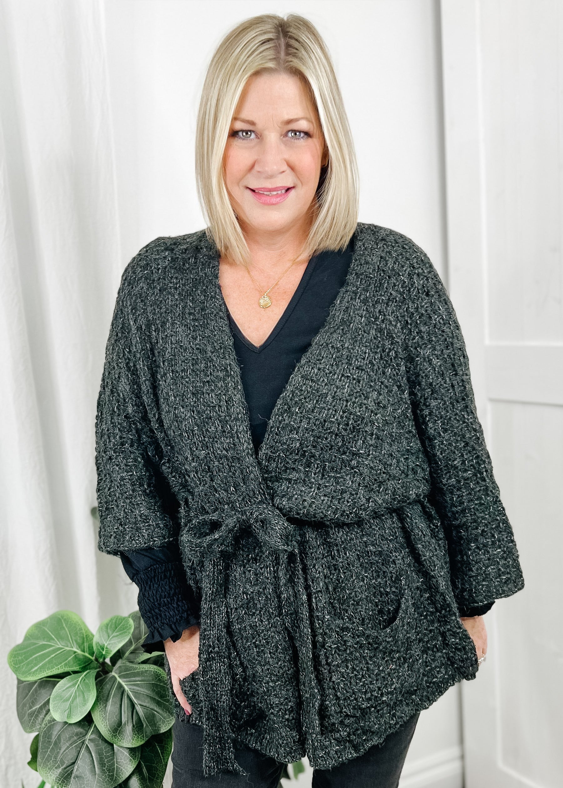 Open front cardigan in a heavy charcoal knit. Cardigan has bell sleeves, open front with attached belt and front pockets.