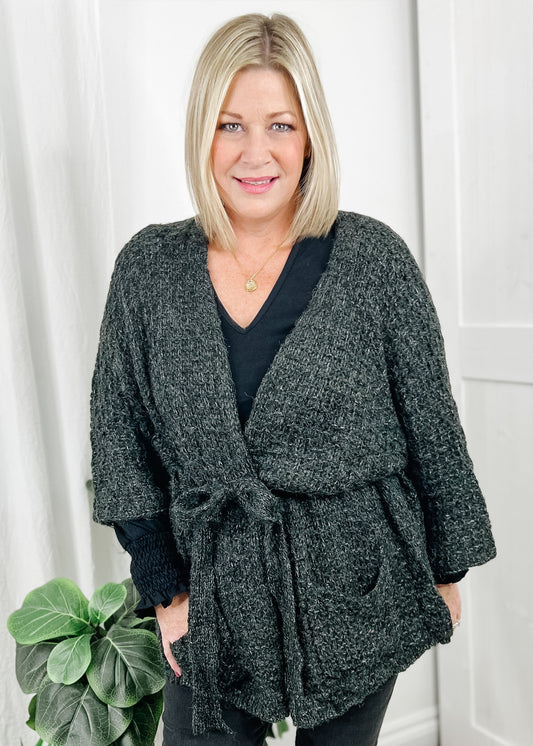 Open front cardigan in a heavy charcoal knit. Cardigan has bell sleeves, open front with attached belt and front pockets.