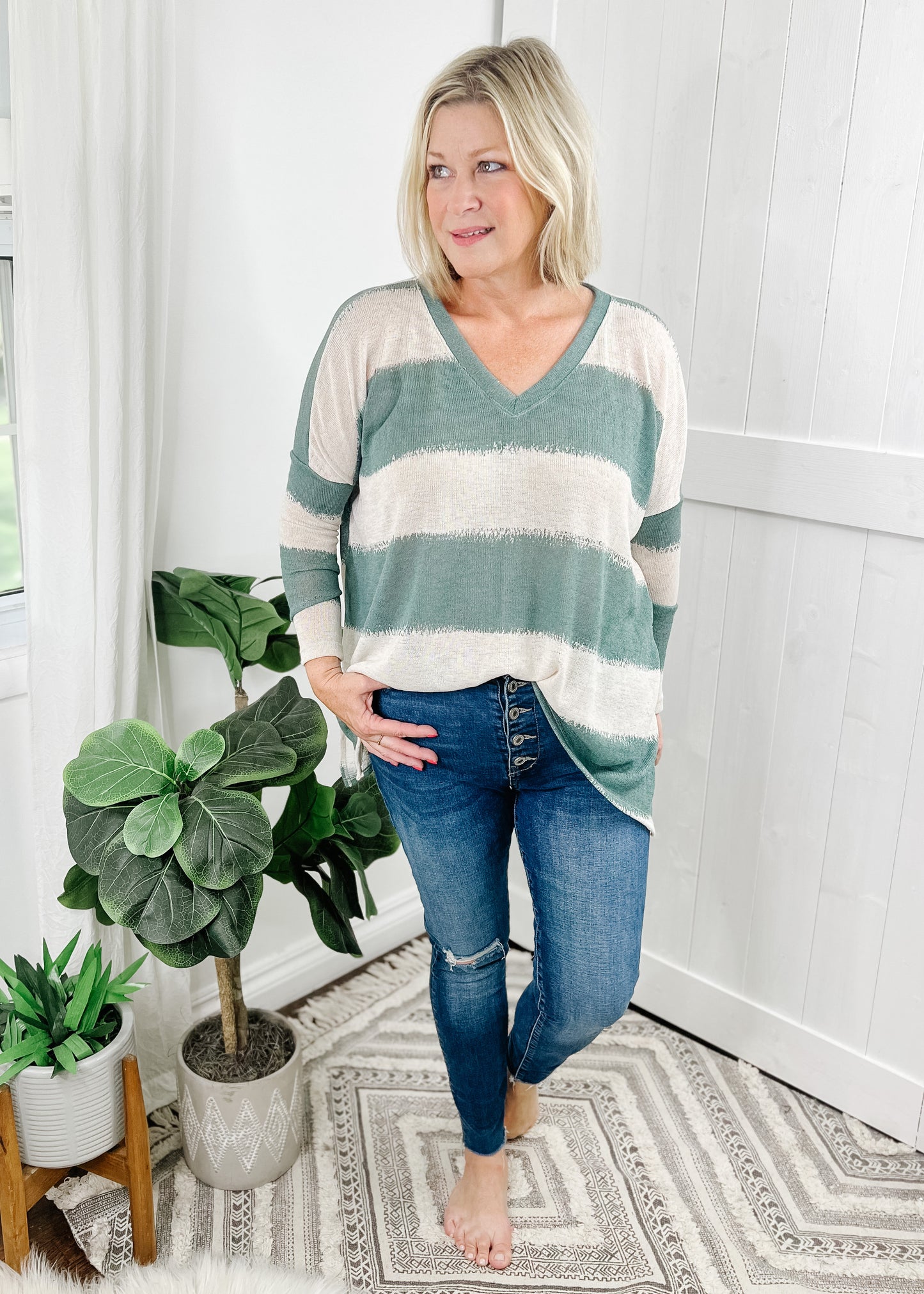 Sage green striped top with contrasting cream stripes, stripes are wide and fade into each other. V-neckline, drop shoulder and relaxed fit.