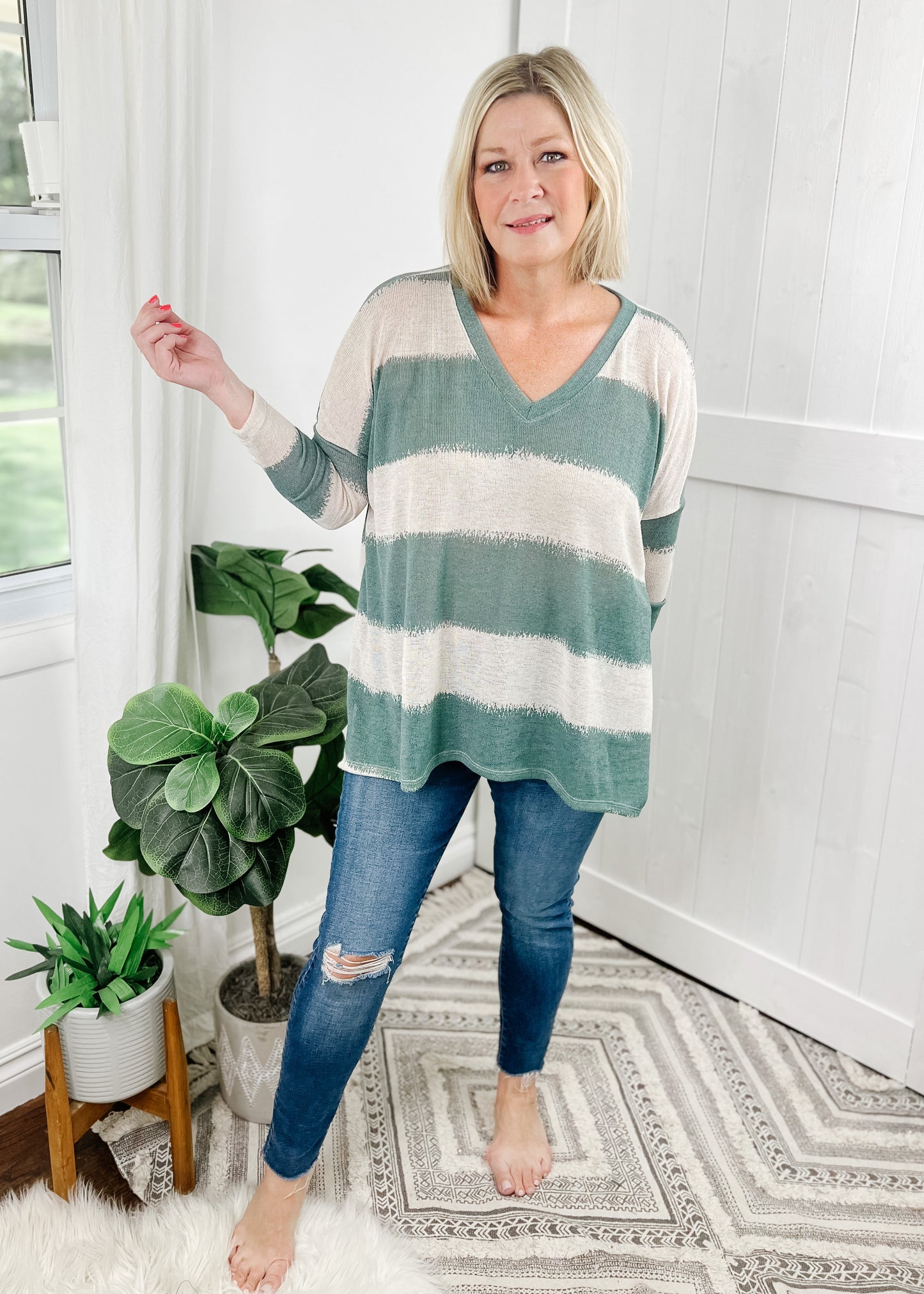 Sage green striped top with contrasting cream stripes, stripes are wide and fade into each other. V-neckline, drop shoulder and relaxed fit.