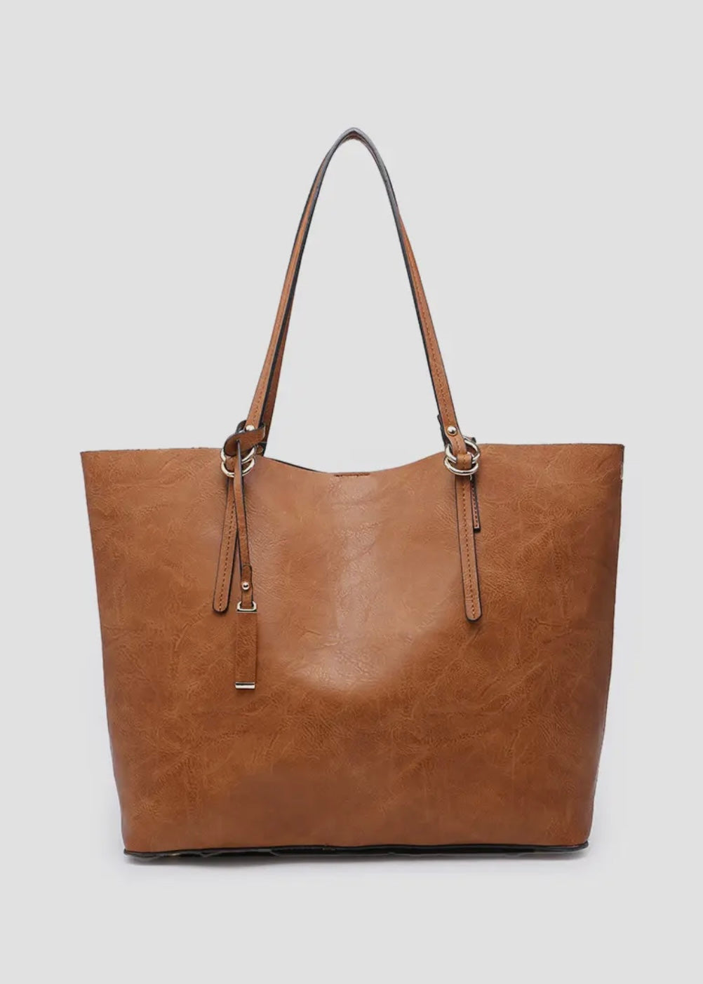 2 in 1 vegan leather tote. 
-Inner Bag: Included with 1 zipper pocket and 2 accessory pockets, herringbone lining
-Straps: Removable adjustable shoulder strap
-Closure: Magnetic snap closure
-Hardware: Gold-tone hardware
-Material: Vegan leather
Shown in brown