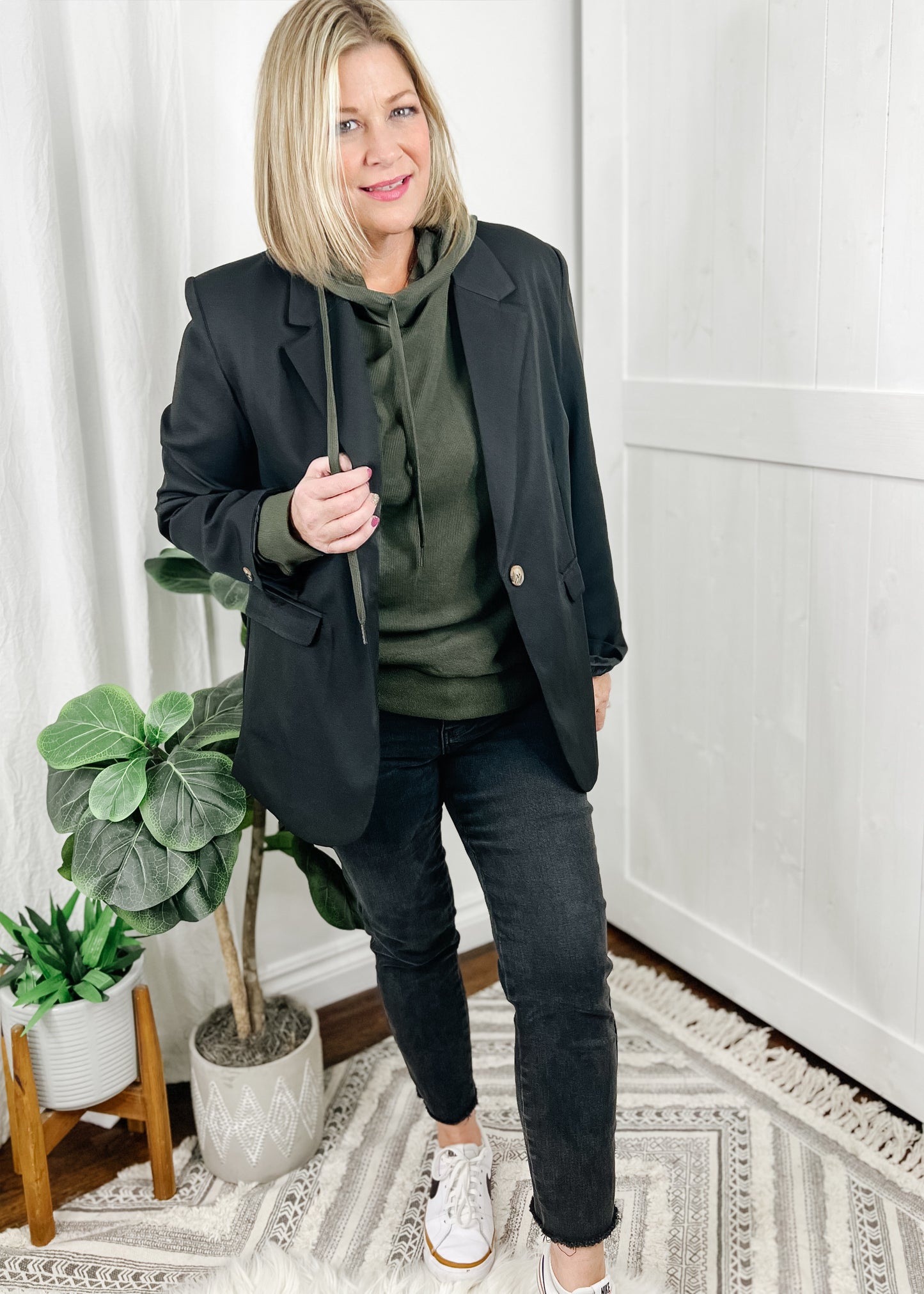 Olive hoodie in a heavy thermal. Top features a side hoodie (opening on the right between center and shoulder) with functional drawstrings and zipper detail also on the side below hoodie opening. Top is long sleeved. Shown with our oversized blazer and black high rise jeans.