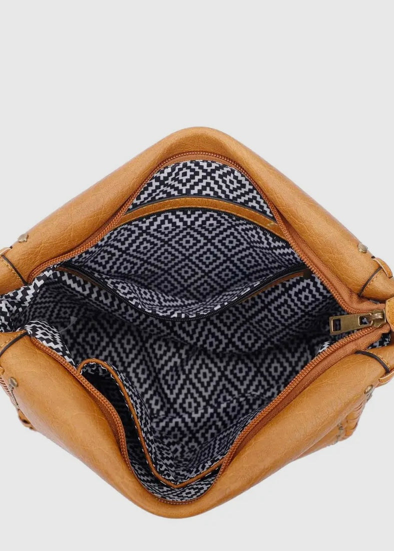 Black vegan leather studded crossbody purse. Purse is 11 x 11 x 4, has gold studded detail around edge, made of a soft vegan leather, top zip closure, back zipper pocket and crossbody strap. Shown in brown.