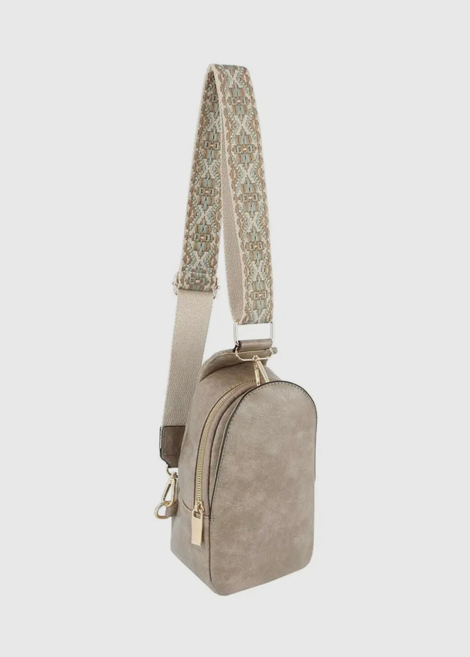 Made with vegan leather and featuring a zip top closure and gold-tone hardware, this bag is perfect for carrying personal items. The adjustable strap and card slots make it a practical choice for on-the-go activities. Dimensions: L 5.75 * H 10.75 * W 3 inches. Shown in gray