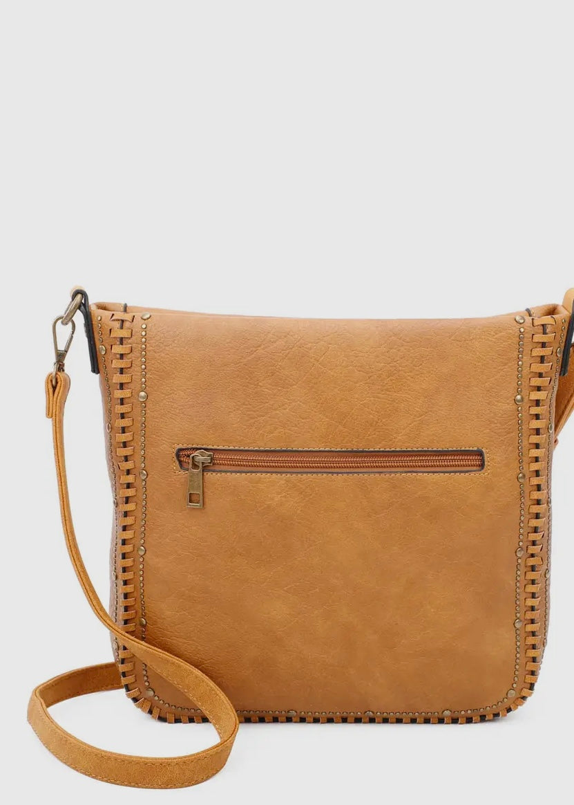 Black vegan leather studded crossbody purse. Purse is 11 x 11 x 4, has gold studded detail around edge, made of a soft vegan leather, top zip closure, back zipper pocket and crossbody strap. Shown in brown.
