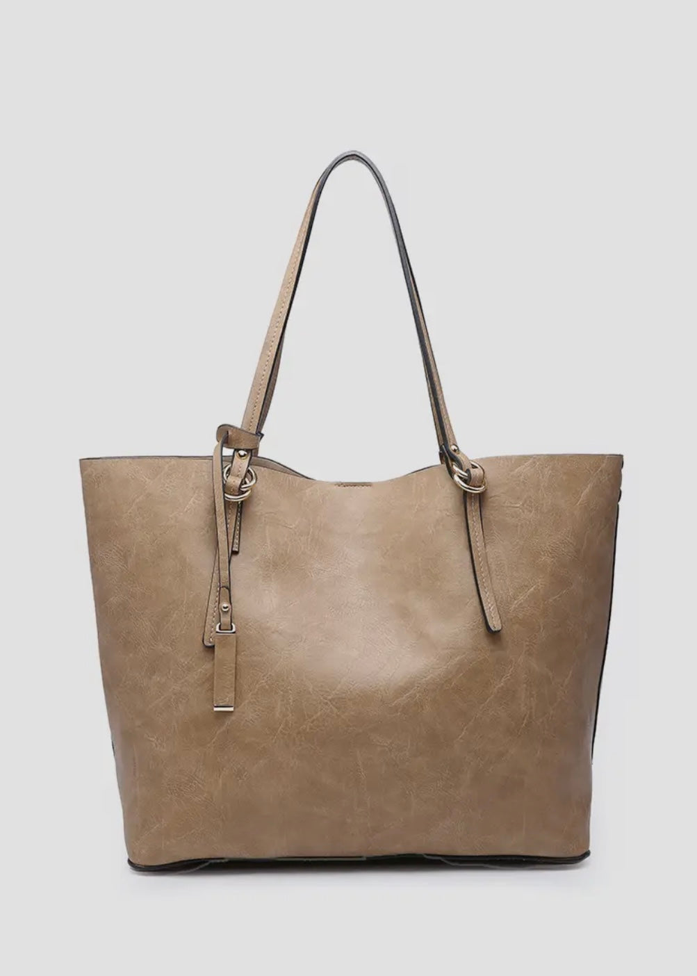 2 in 1 vegan leather tote. 
-Inner Bag: Included with 1 zipper pocket and 2 accessory pockets, herringbone lining
-Straps: Removable adjustable shoulder strap
-Closure: Magnetic snap closure
-Hardware: Gold-tone hardware
-Material: Vegan leather
Shown in taupe
