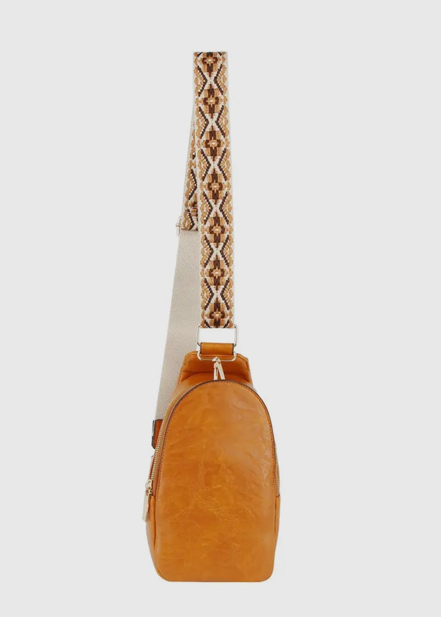 Made with vegan leather and featuring a zip top closure and gold-tone hardware, this bag is perfect for carrying personal items. The adjustable strap and card slots make it a practical choice for on-the-go activities. Dimensions: L 5.75 * H 10.75 * W 3 inches. Shown in brown