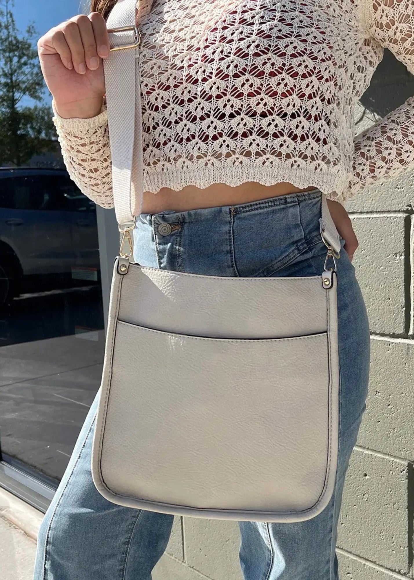 Vegan leather crossbody purse with adjustable black guitar strap. Front has a snap slip pocket, top zip closure to keep your belongings secure.  Dimensions of 10x10x2.5 inches. Shown in black.