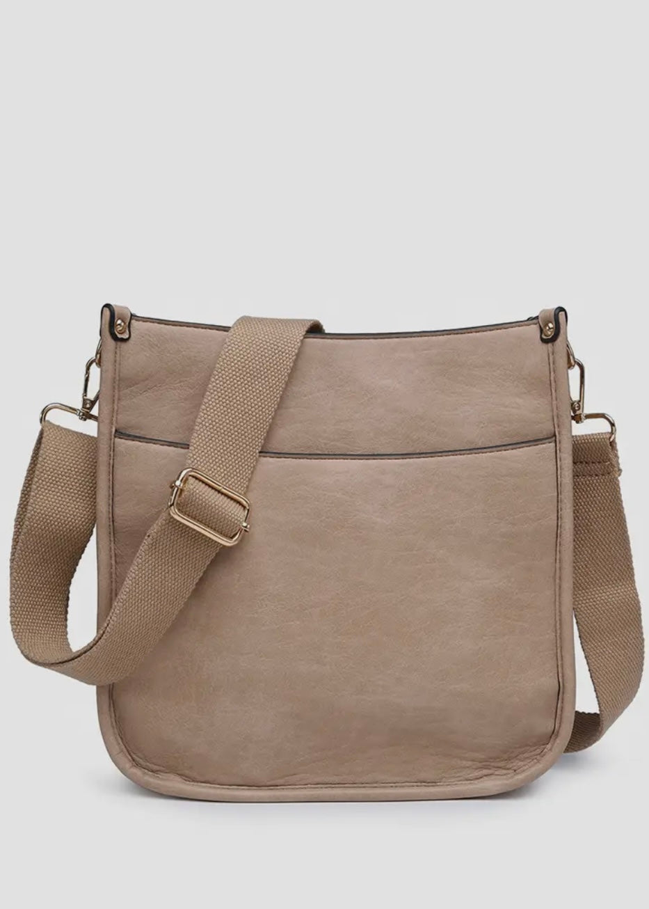 Vegan leather crossbody purse with adjustable black guitar strap. Front has a snap slip pocket, top zip closure to keep your belongings secure.  Dimensions of 10x10x2.5 inches. Shown in tan.