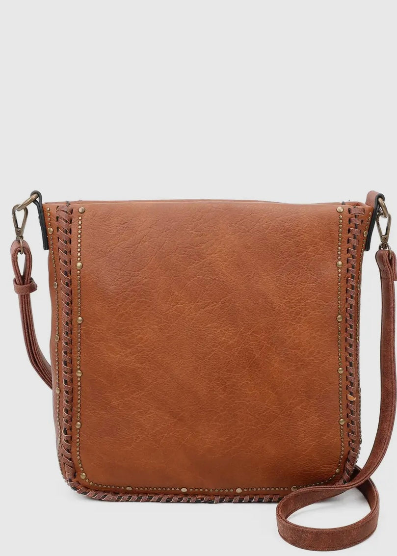 Black vegan leather studded crossbody purse. Purse is 11 x 11 x 4, has gold studded detail around edge, made of a soft vegan leather, top zip closure, back zipper pocket and crossbody strap. Shown in brown.