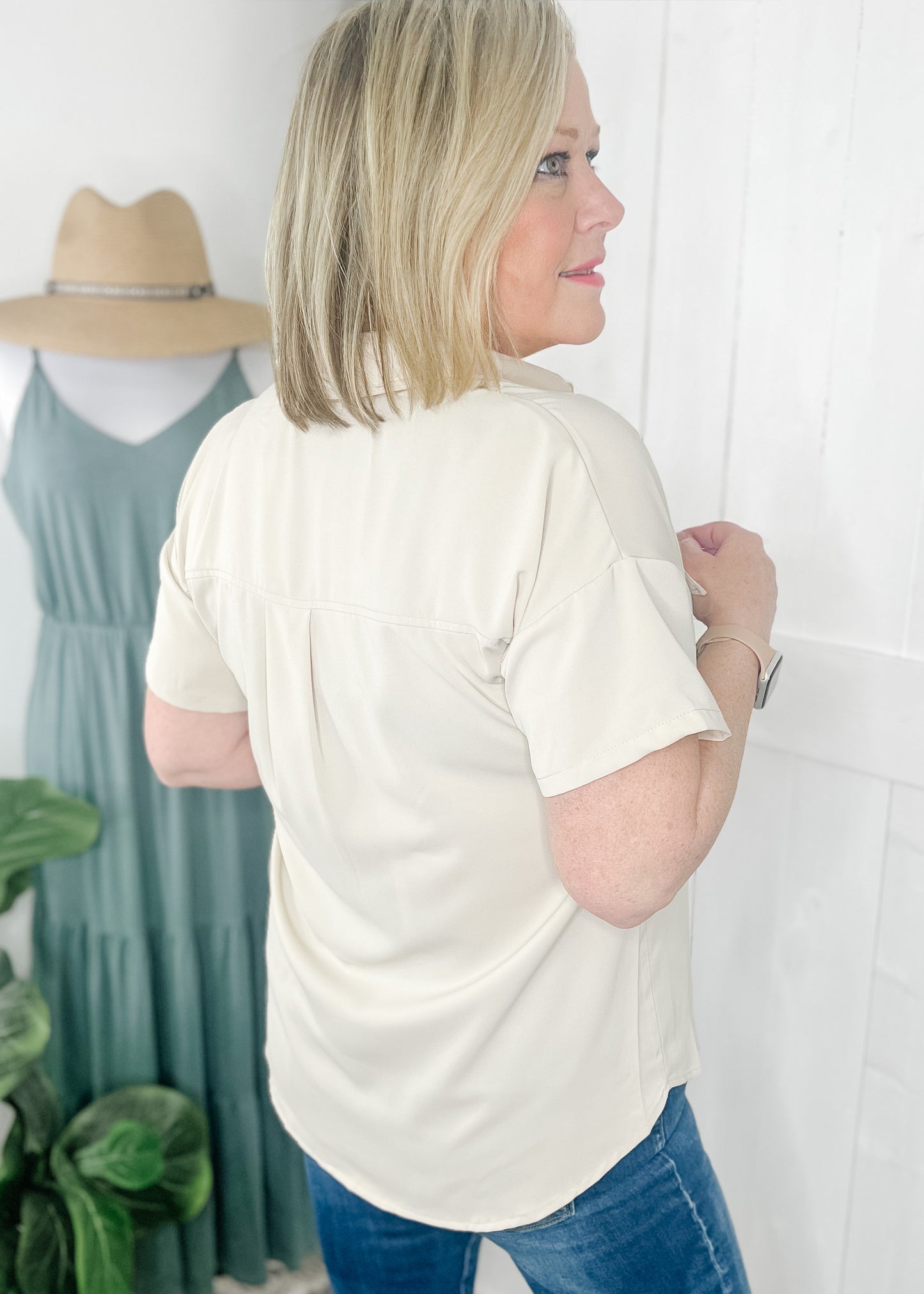Classic short sleeve button up in a. soft beige with collar, flap chest pockets and rounded hemline.