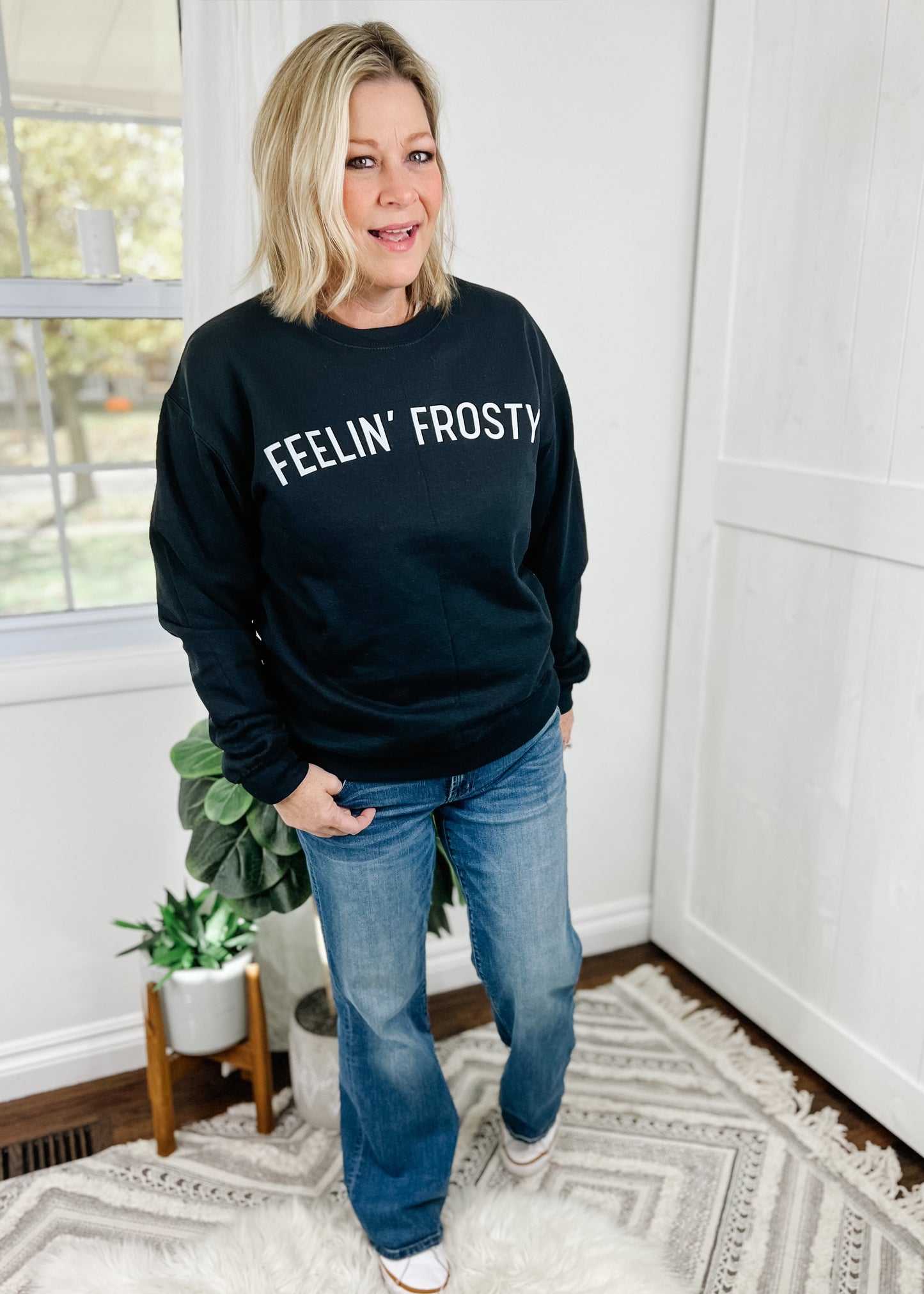 Black sweatshirt with Feelin' Frosty across the chest in white. This is a standard black crew neck sweatshirt with a unisex fit.