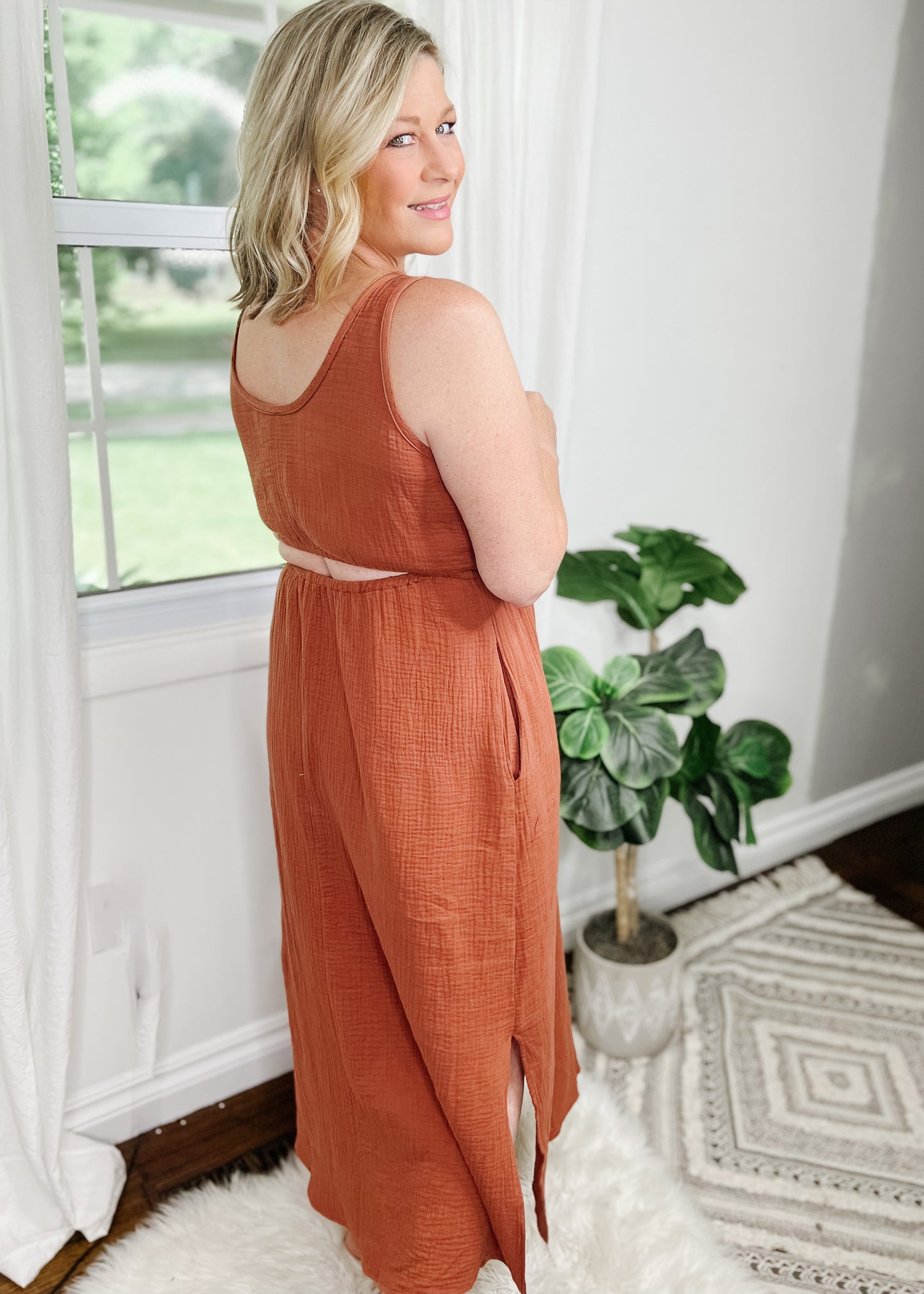 Midi cut out dress in a beautiful terracotta and light gauze fabric. Tank top style sleeves with 2 rows of elastic about an Ince apart for some pretty details. Side slits on bottom curved hemline. Cut out detail is in back above waistline.