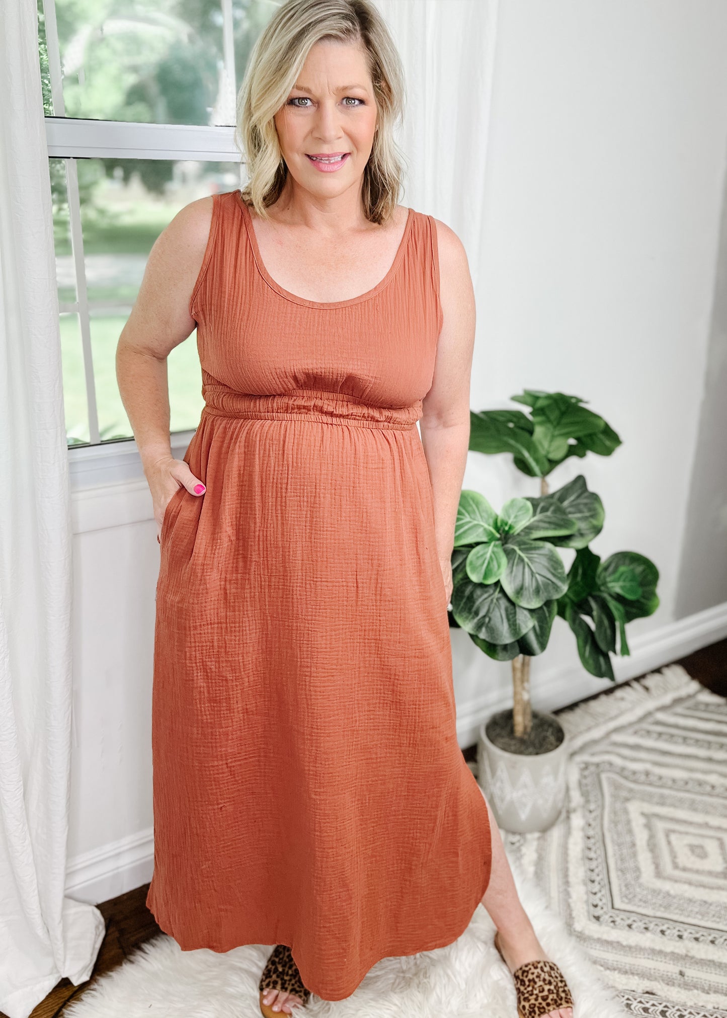Midi cut out dress in a beautiful terracotta and light gauze fabric. Tank top style sleeves with 2 rows of elastic about an Ince apart for some pretty details. Side slits on bottom curved hemline. Cut out detail is in back above waistline.