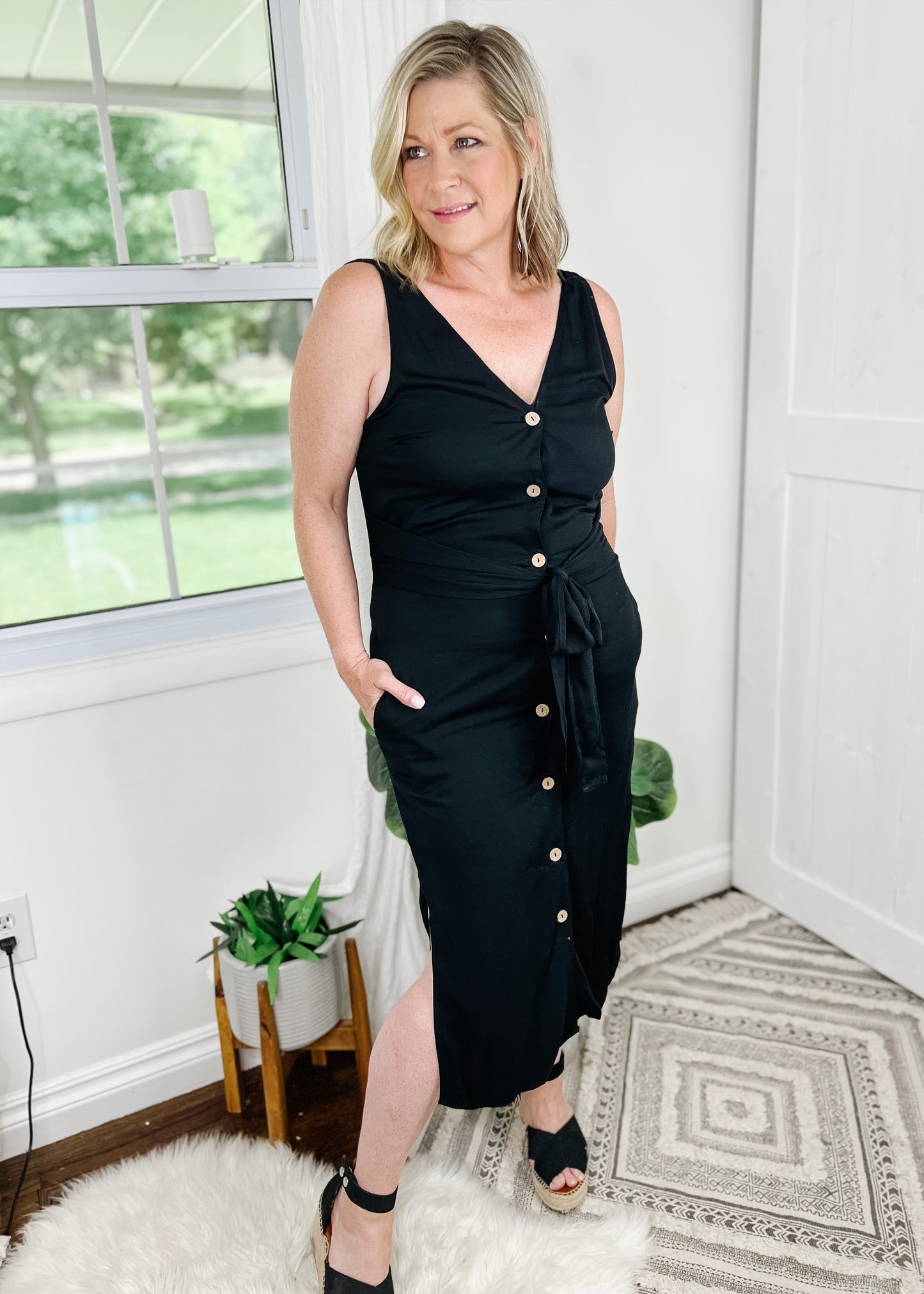Black midi dress. Black button up dress with functional wood buttons, V-Neckline, sleeveless and side slits. Dress also features pockets.