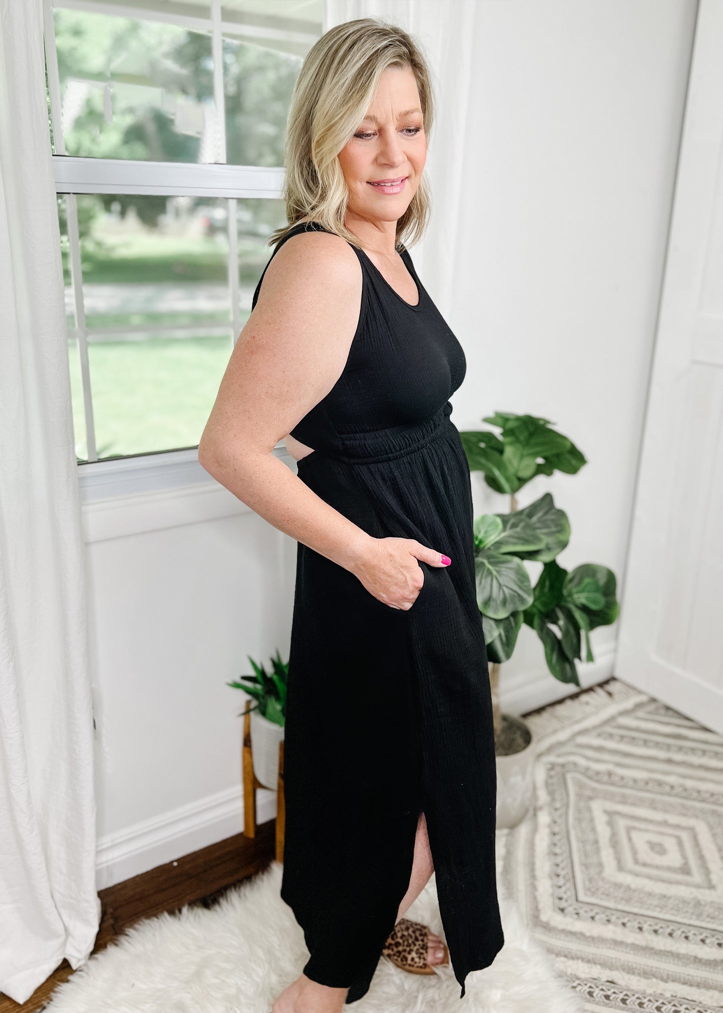 Black midi dress with cut out details in a light gauze fabric. Tank top style sleeves with 2 rows of elastic about an Inch apart for some pretty details. Side slits on bottom curved hemline. Cut out detail is in back above waistline.