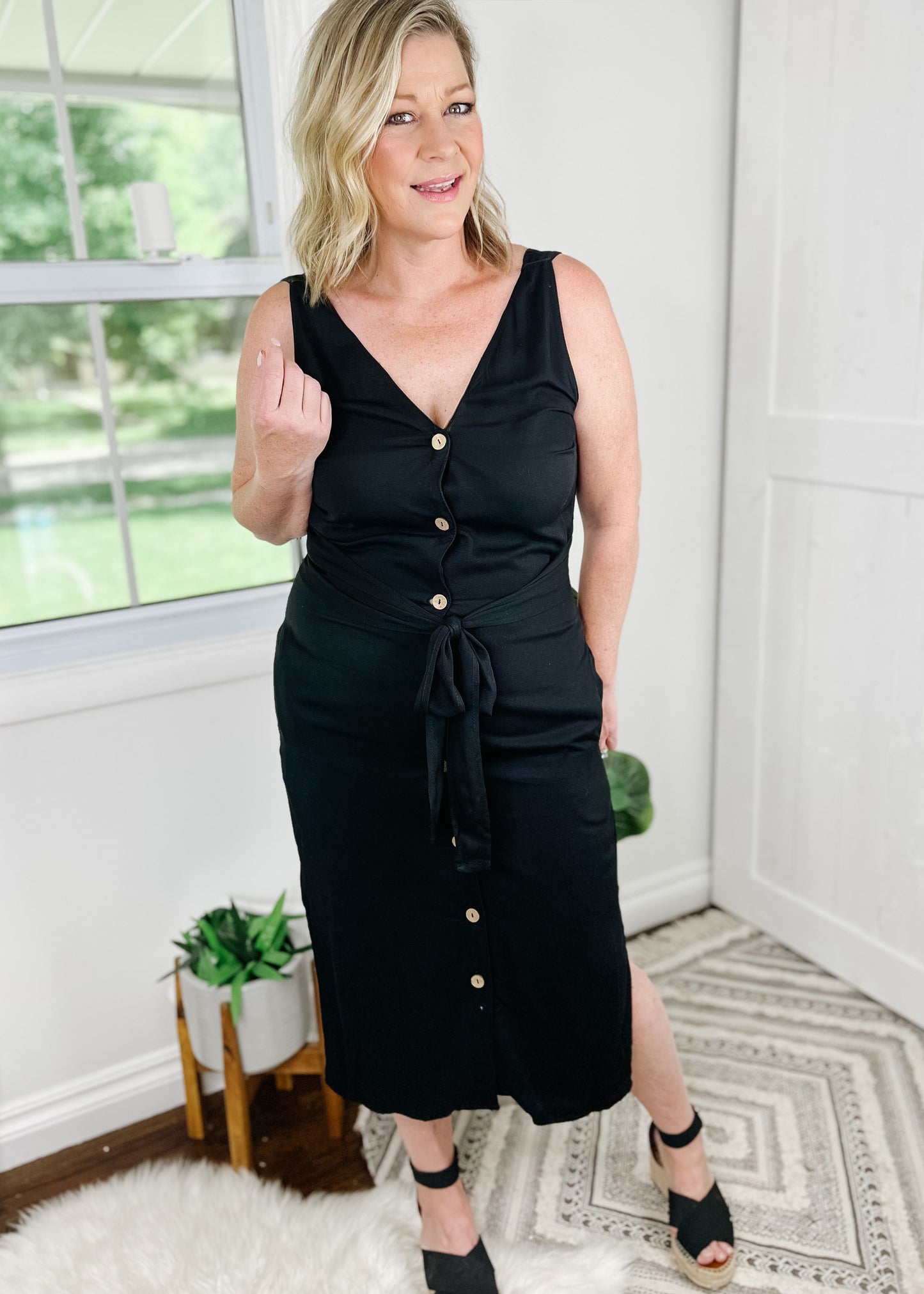 Black midi dress. Black button up dress with functional wood buttons, V-Neckline, sleeveless and side slits. Dress also features pockets.