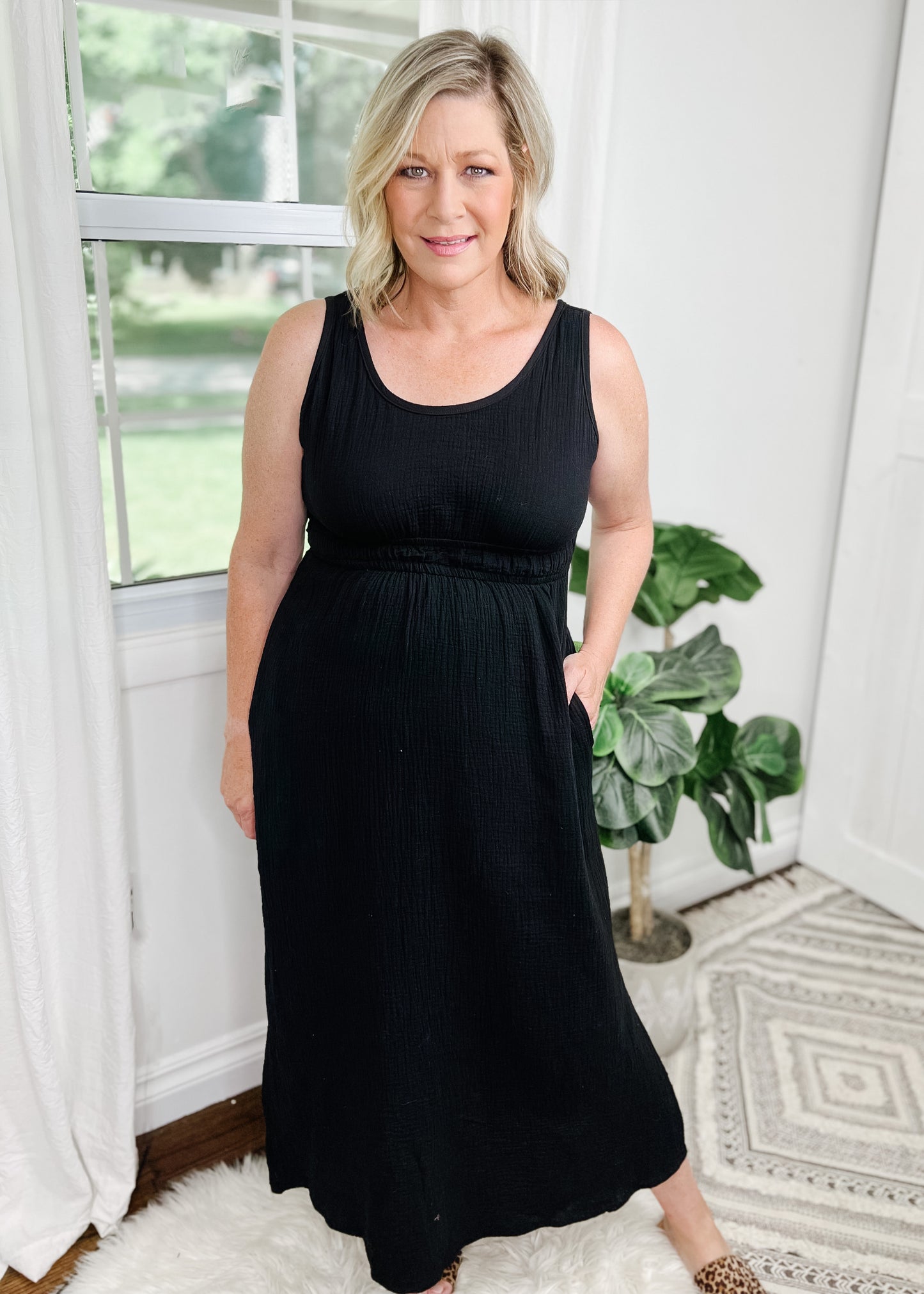 Black midi dress with cut out details in a light gauze fabric. Tank top style sleeves with 2 rows of elastic about an Inch apart for some pretty details. Side slits on bottom curved hemline. Cut out detail is in back above waistline.
