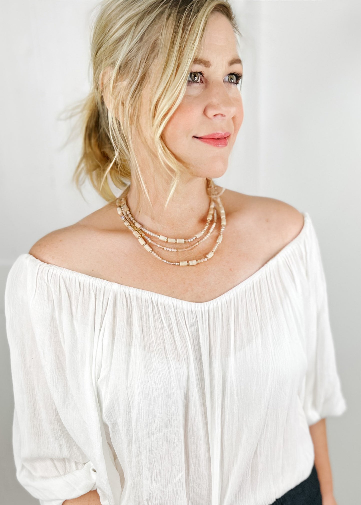 Beaded necklace with multi beads in small rounded frost and gold beads with larger tan beads sporadically throughout