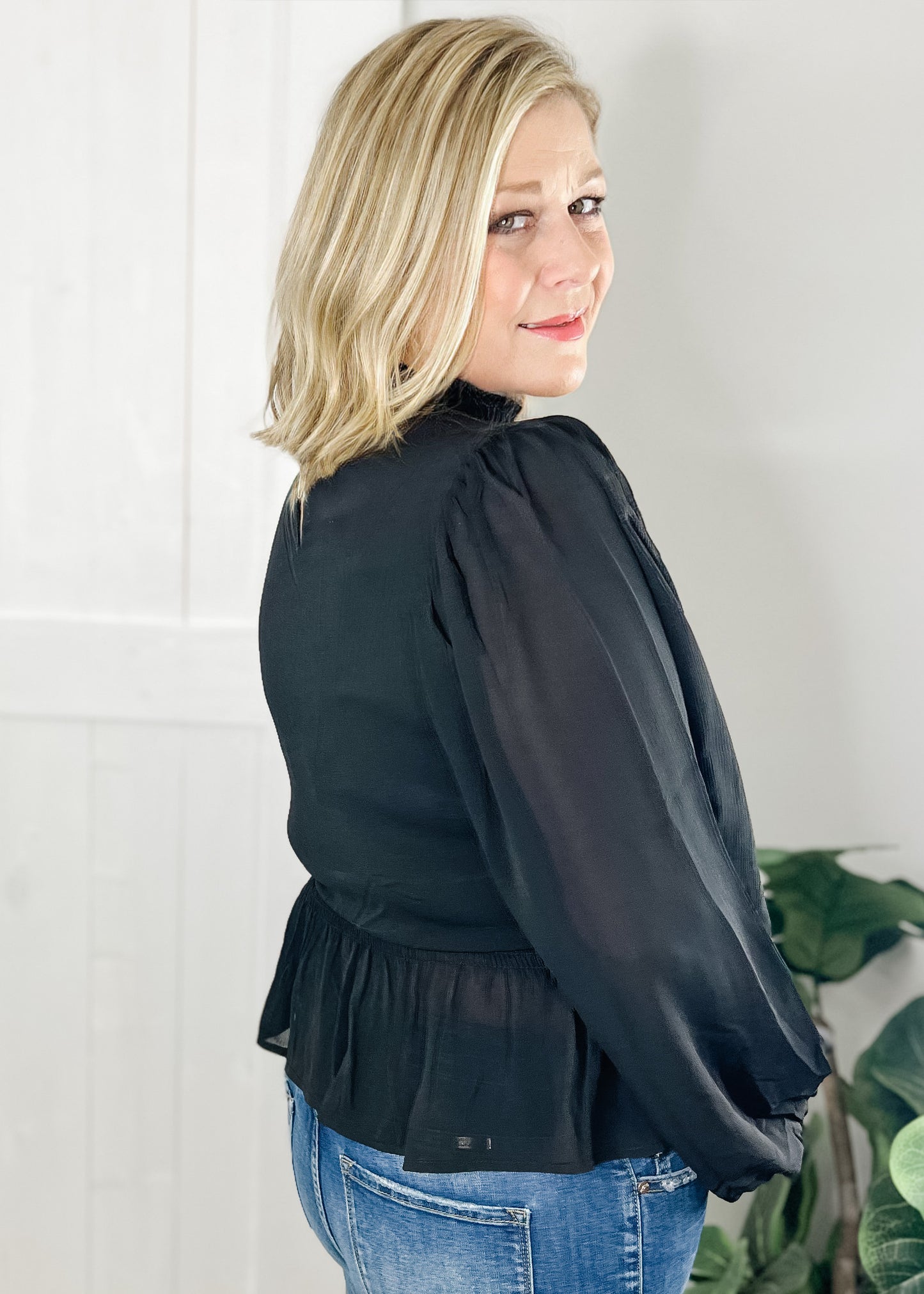 Black peplum blouse with long sleeves double layered bodice with smocked waist with ruffle bottom hemline and smocked mock neck.