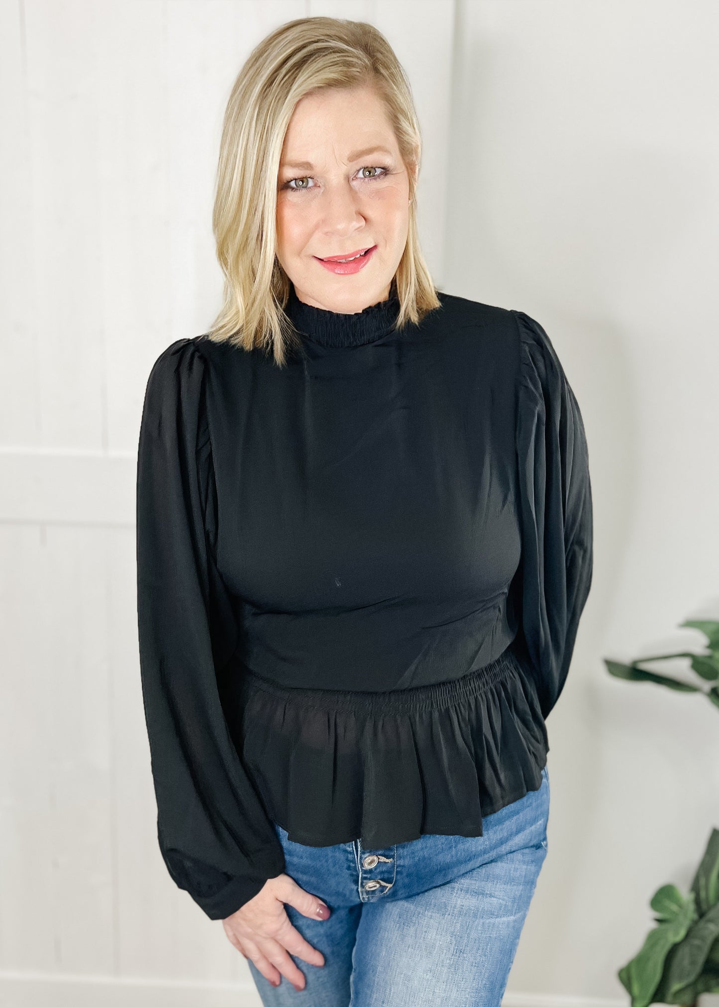 Black peplum blouse with long sleeves double layered bodice with smocked waist with ruffle bottom hemline and smocked mock neck.