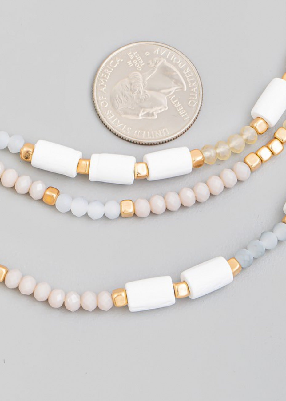 Beaded necklace with multi beads in small rounded frost and gold beads with larger white beads sporadically throughout