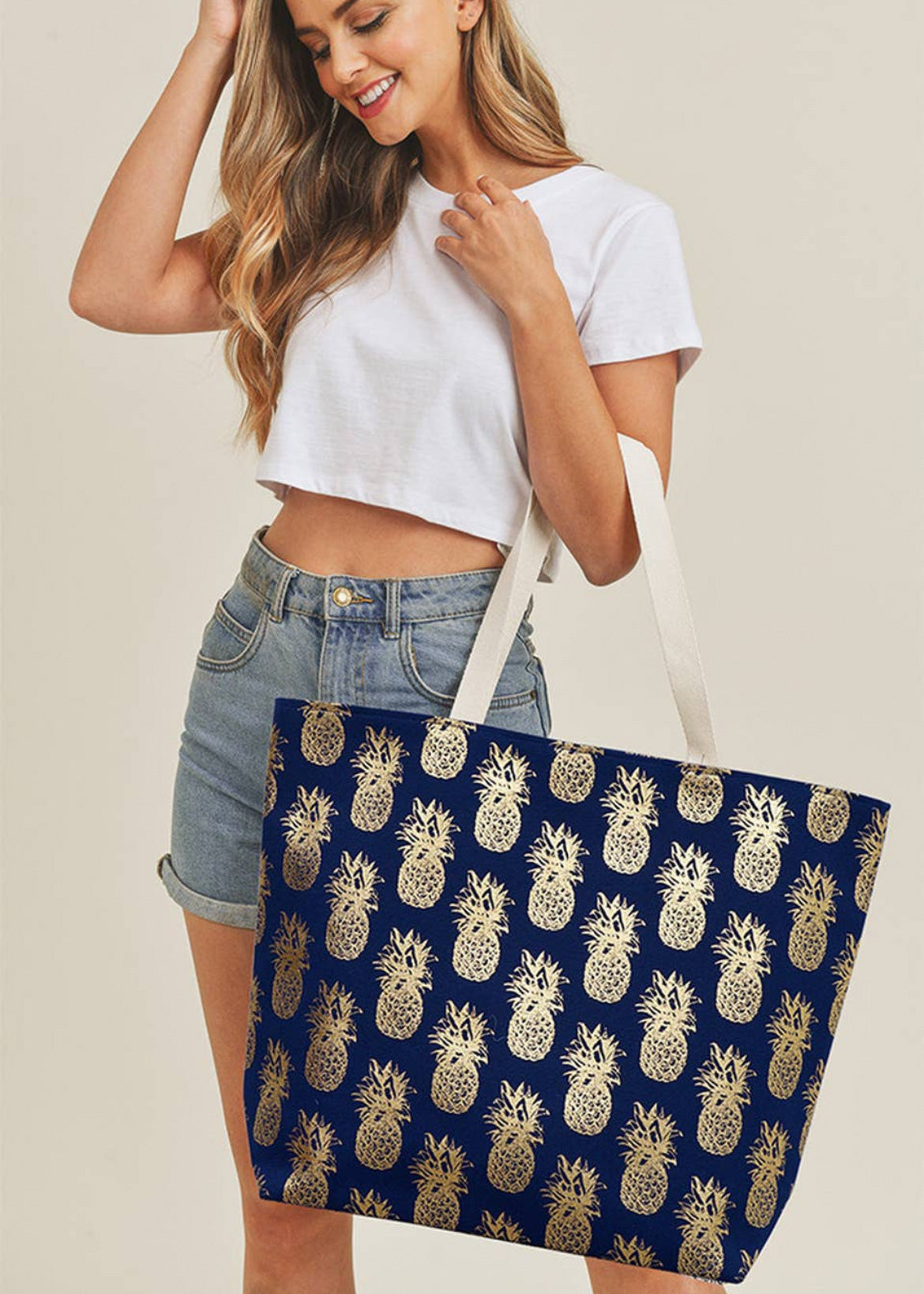 Navy beach bag with gold foil pineapples imprinted  throughout.  Bag has a snap closure and long straps. 