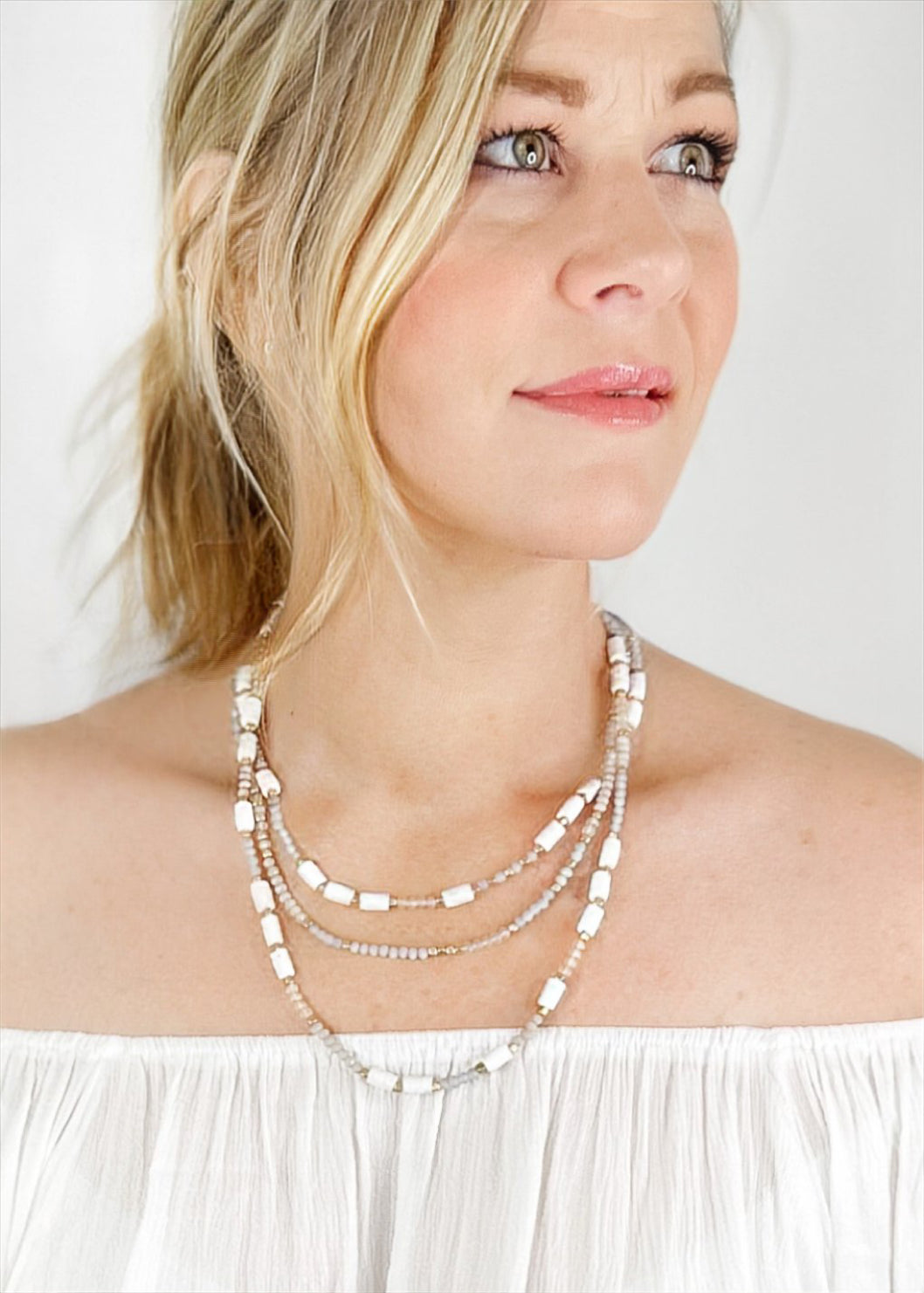 Beaded necklace with multi beads in small rounded frost and gold beads with larger white beads sporadically throughout