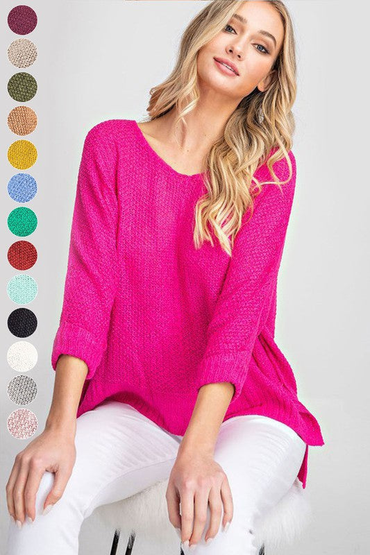 Knit sweater in a bright pink color with 3/4 cuffed sleeves, v-neckline and side slits. 