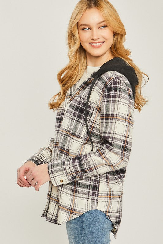 Plaid flannel in cream, black and brown with front button up and pockets. Flannel features a black attached hoodie wit functional drawstrings. 