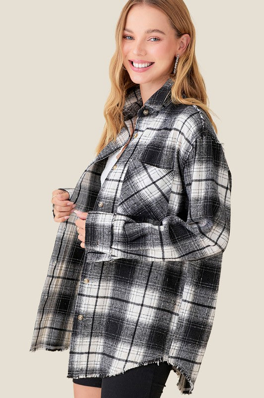 Black and white plaid button up flannel with raw hemline, relaxed fit and front pockets.