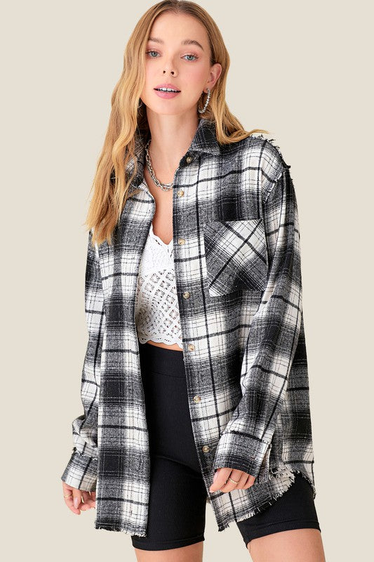 Black and white plaid button up flannel with raw hemline, relaxed fit and front pockets.