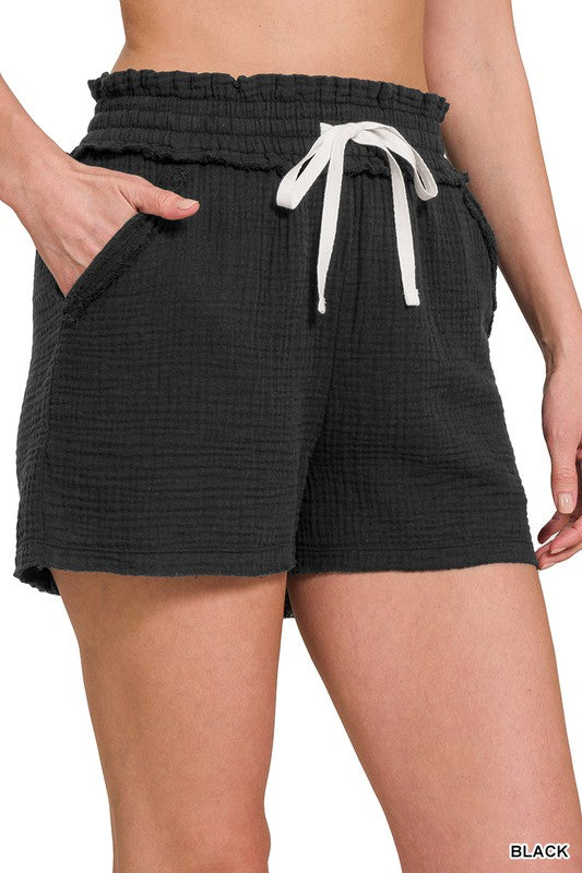 Drawstring shorts in a light muslin fabric with functional drawstrings. Features pockets and elastic waist. Shown in black.