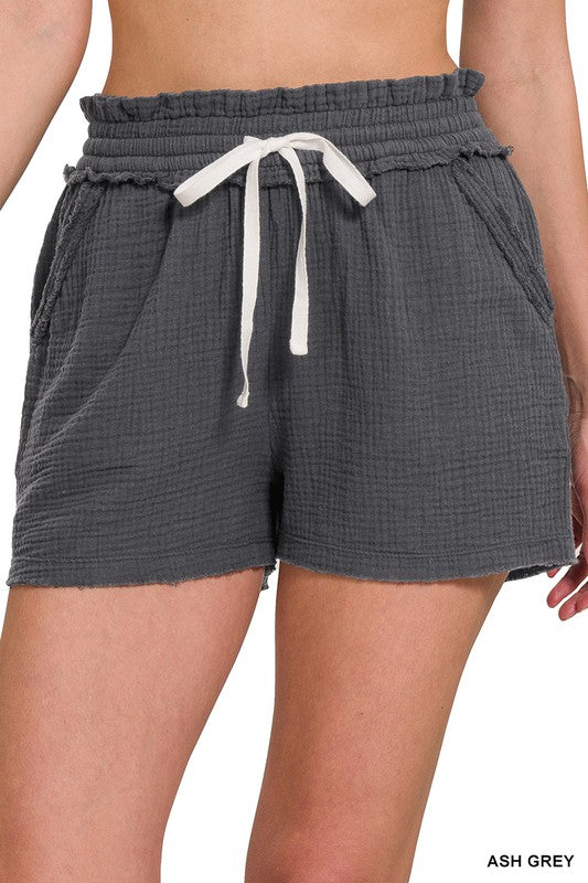 Drawstring shorts in a light muslin fabric with functional drawstrings. Features pockets and elastic waist. Shown in charcoal.