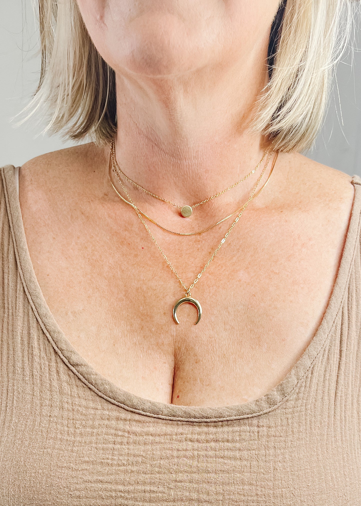 Three layer gold crescent moon necklace. First layer is in a thin chain with a small 1/4 inch solid gold circle, second layer is a plain this gold chain, last layer in also a thin chain with the crescent moon that is approximently 1 inch. 