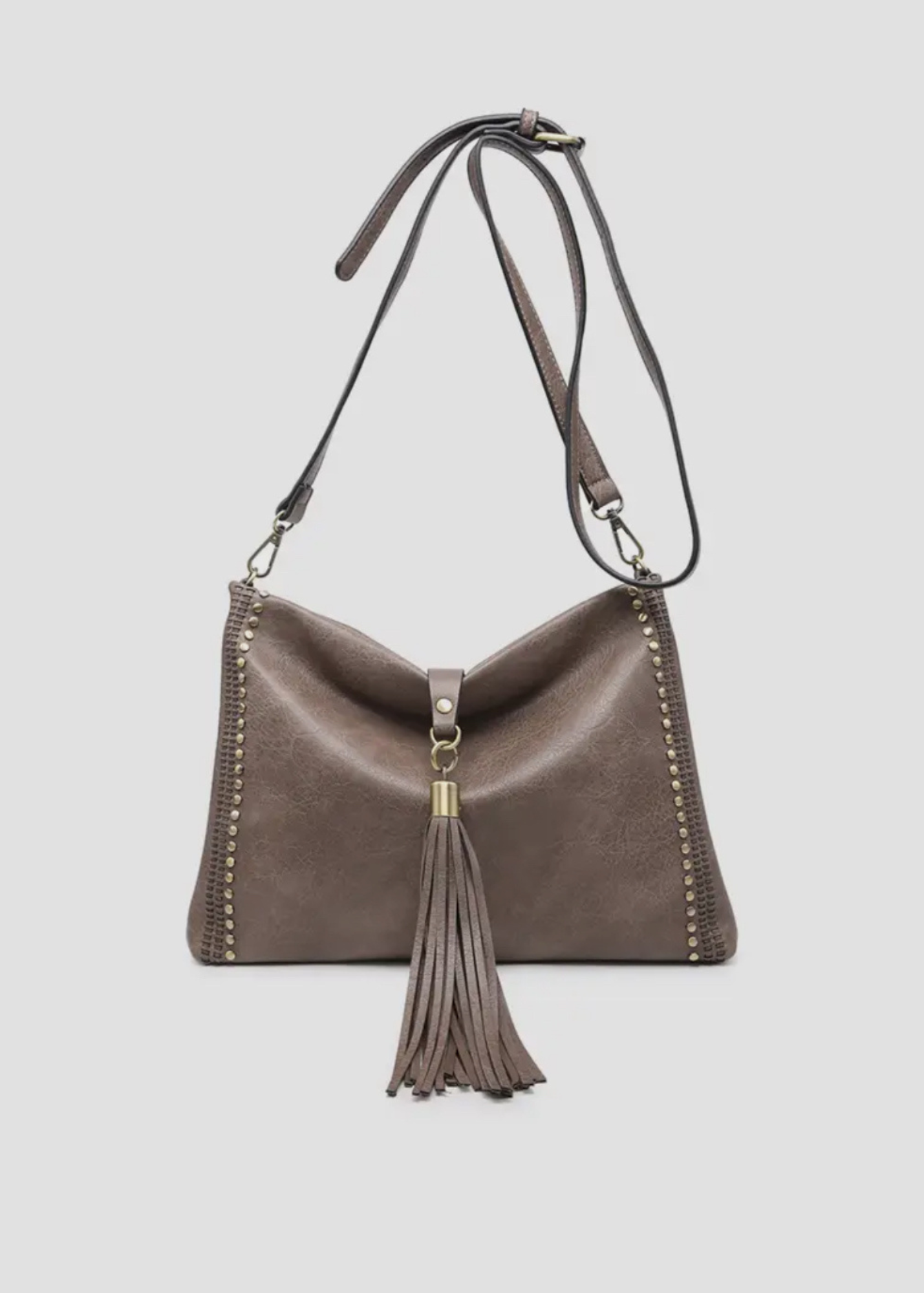 Coco color  purse made of soft vegan leather. Purse is rectangular with silver studs going up the sides and a ling tassel wit silver hardware that folds over the top to close purse. Strap is crossbody length and is adjustable. 