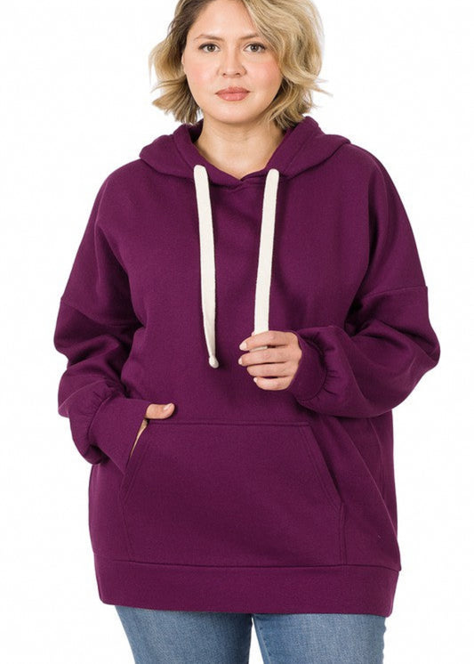 Oversized hoodie sweatshirt with kangaroo front pocket and cream drawstrings. Shown in dark plum in plus size. 