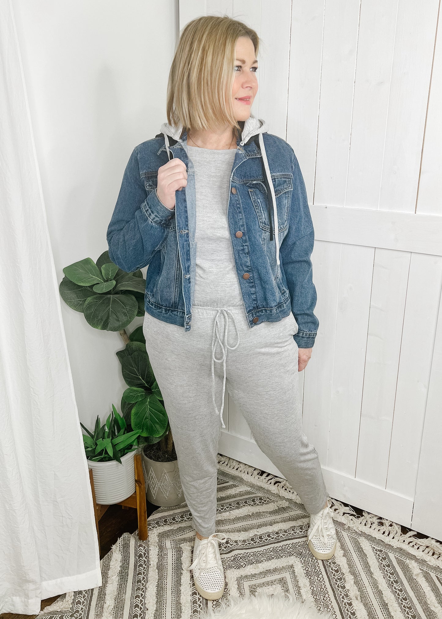 Gray jumpsuit with boat neckline, short sleeves and tapered legs. Jumpsuit has side pockets and elastic waist with faux drawstring.  Shown with our Denim Jacket With Hoodie. 