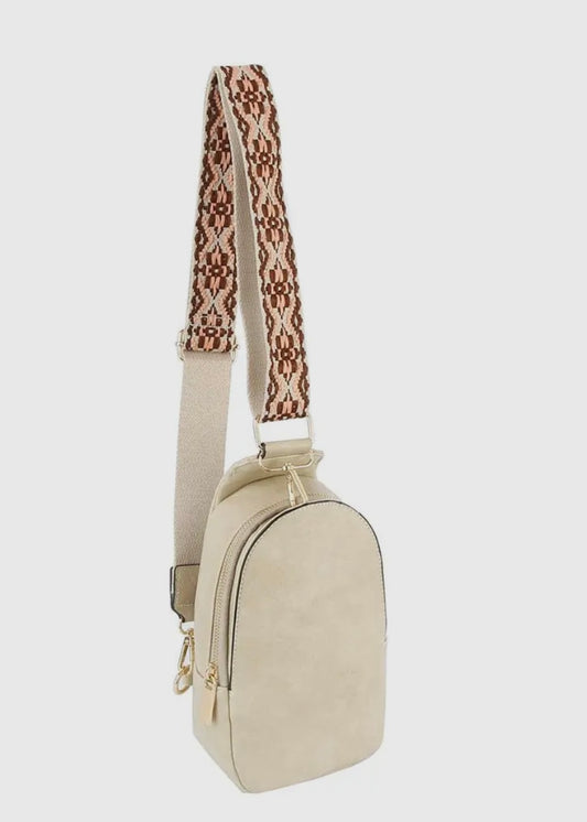 Sling bag made of soft vegan leather and featuring a zip top closure and gold-tone hardware. Has an adjustable strap and card slots make it a practical choice for on-the-go activities. Dimensions: L 5.75 * H 10.75 * W 3 inches. Shown in beige