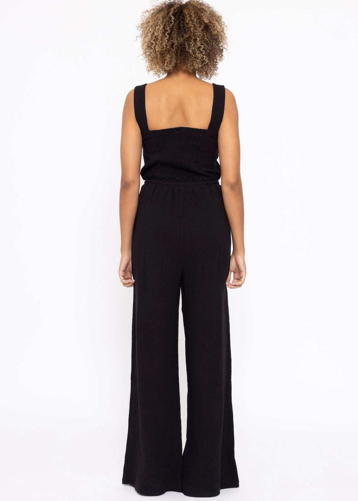 100% cotton Gauze Wide Leg Jumpsuit in black. Features a sweetheart neckline and smocked back panel. Thick 1 1/2 inch straps, side pockets and wide leg. 