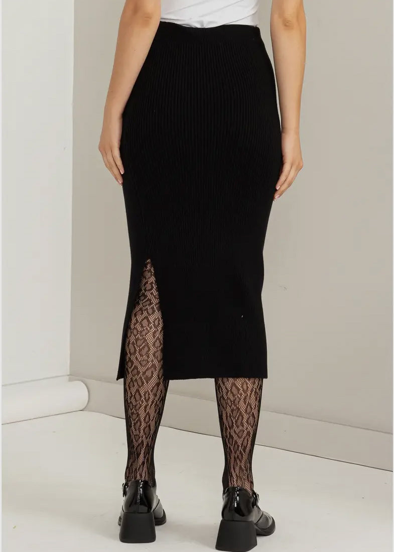 Black sweater skirt in a ribbed knit. Skirt has an elastic waist, side slit and midi length. Knit is soft with stretch. 