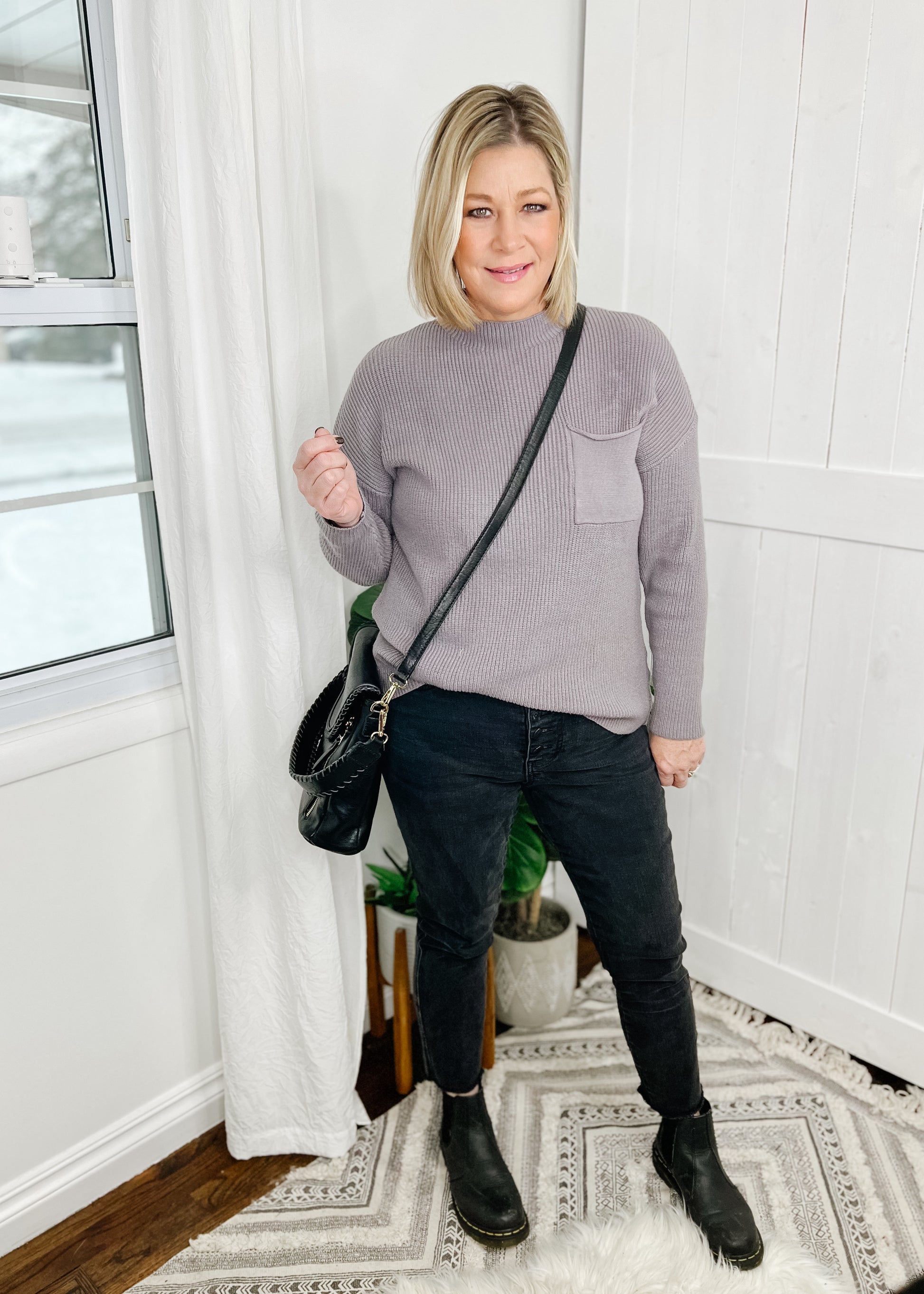Gray sweater with a ribbed knit and a solid knit front pocket on left breast. Sweater features a mock neckline, drop shoulder and long sleeves. 