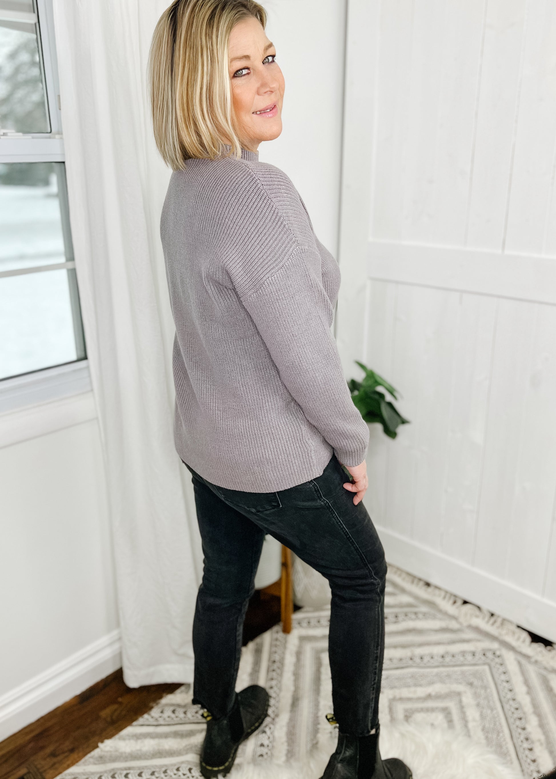 Gray sweater with a ribbed knit and a solid knit front pocket on left breast. Sweater features a mock neckline, drop shoulder and long sleeves. 