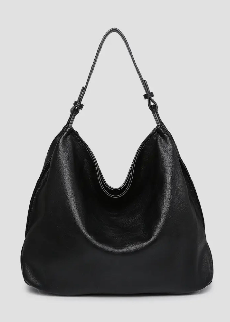 Black vegan leather slouch bag/tote with inner slip and zip pocket and inner zip compartment. Bag has a zipper closure, back zipper pocket and is made of a soft vegan leather. Size: 13x16x5.5