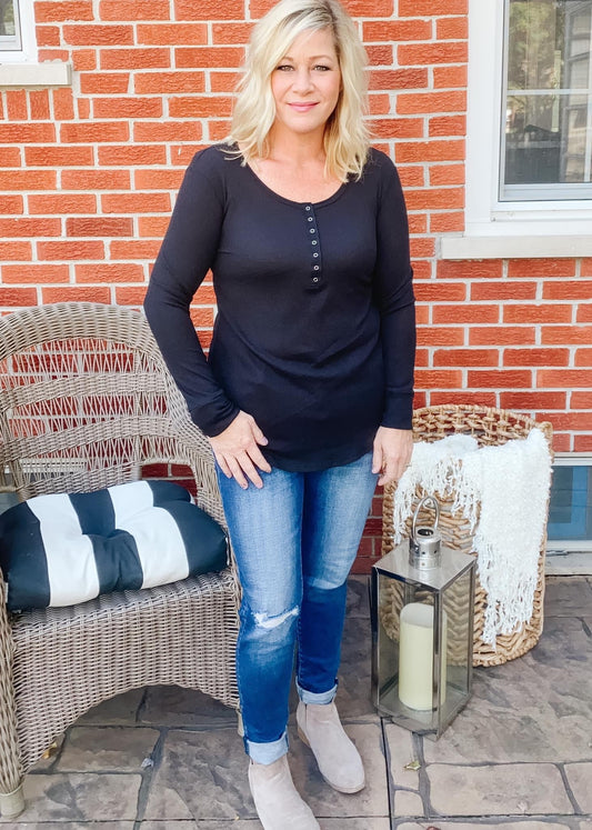 Black waffle knit Henley top with long sleeves, curved hemline and from snap buttons at neckline. 