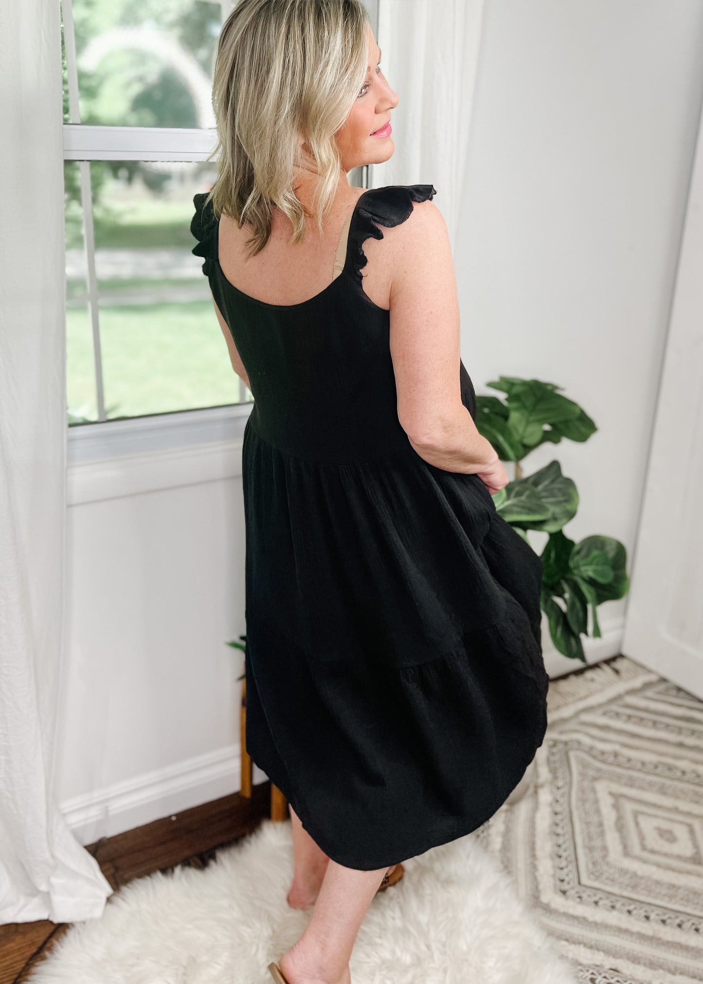 Black midi dress in a tiered style with ruffle tank straps. Made from a soft muslin fabric and is lined.