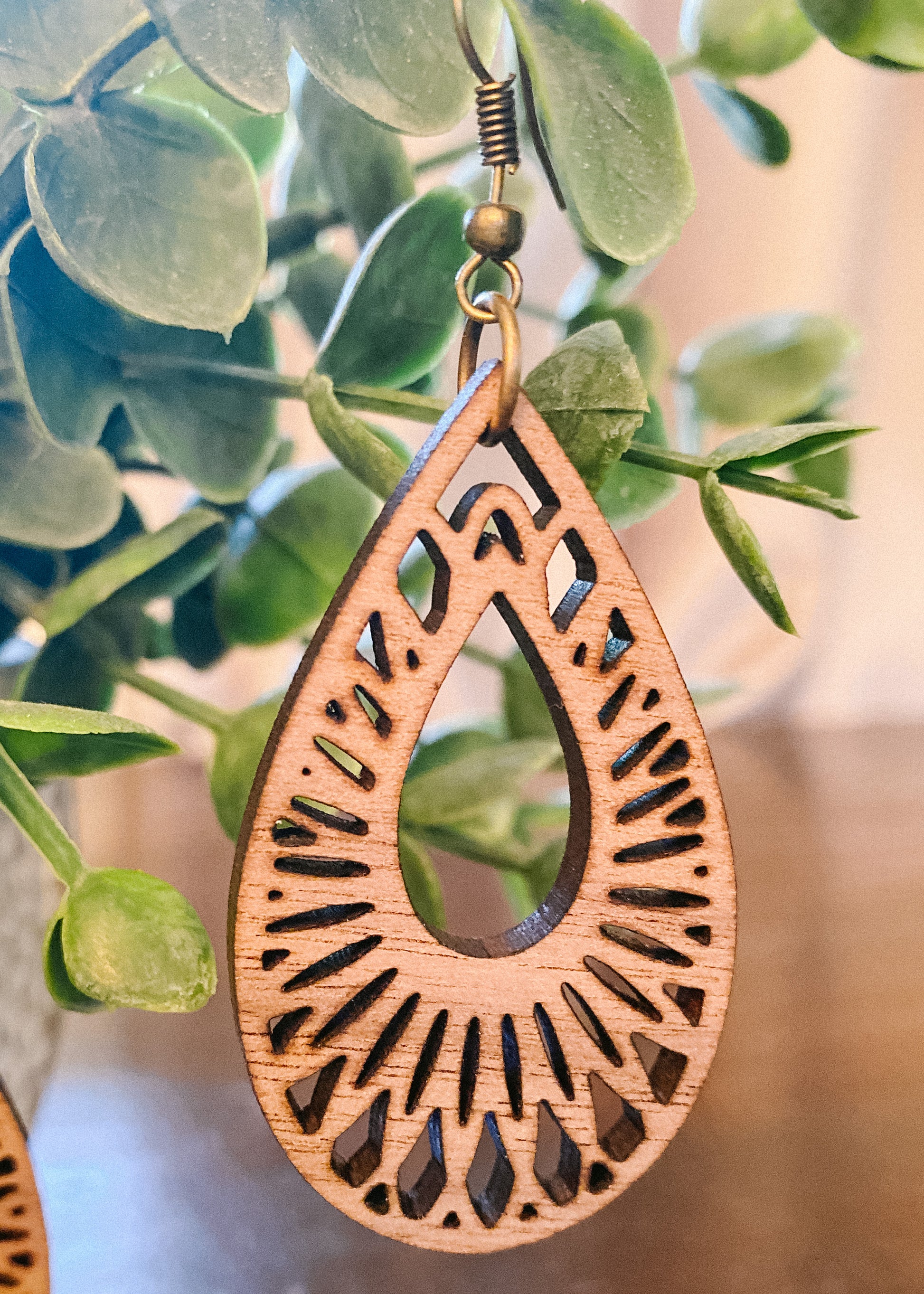 Natural wood teardrop earrings with cutout details and gold hardware.