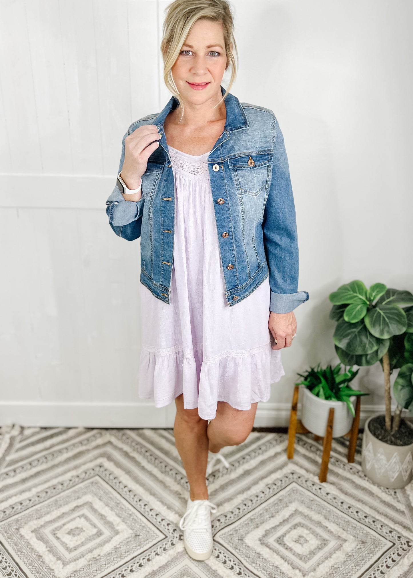 Lilac dress with tassel ties at shoulders, slight v neckline with lace boarder. Dress seis knee length and has a ruffle bottom. Shown with our short denim jacket. 